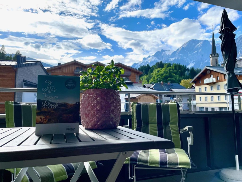 Gemütlicher Balkon mit Blick auf die Alpen, Pflanzen, Prospekt für den Sommerurlaub.